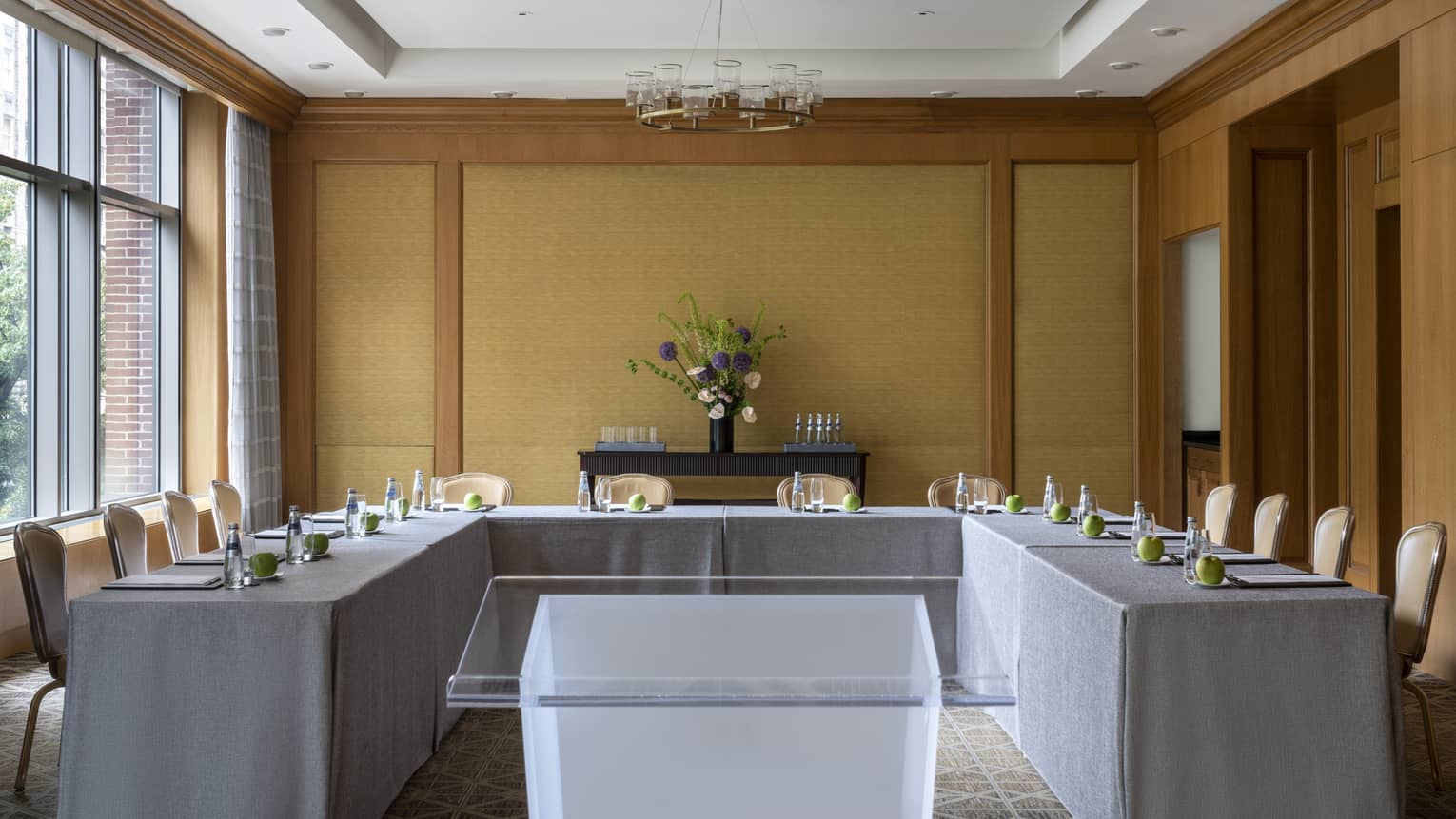 A U-shaped table with grey cloth and a clear podium in the middle.