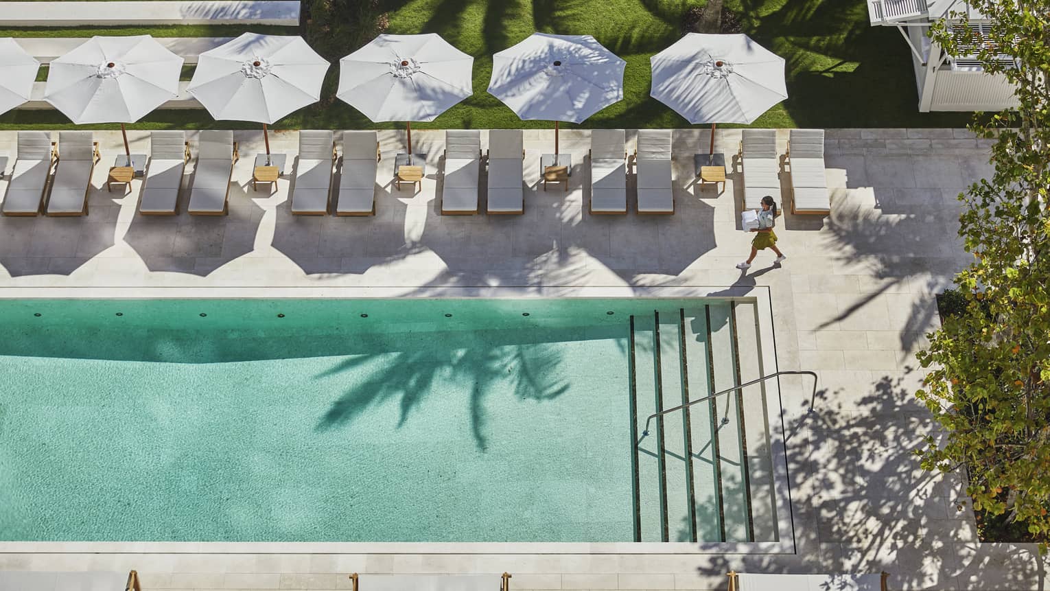 Aerial view of adult outdoor swimming pool, person walking across patio deck