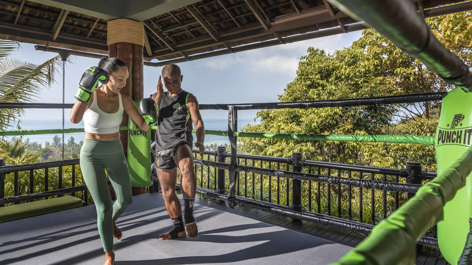 Muay Thai trainer teaches woman in outdoor ring