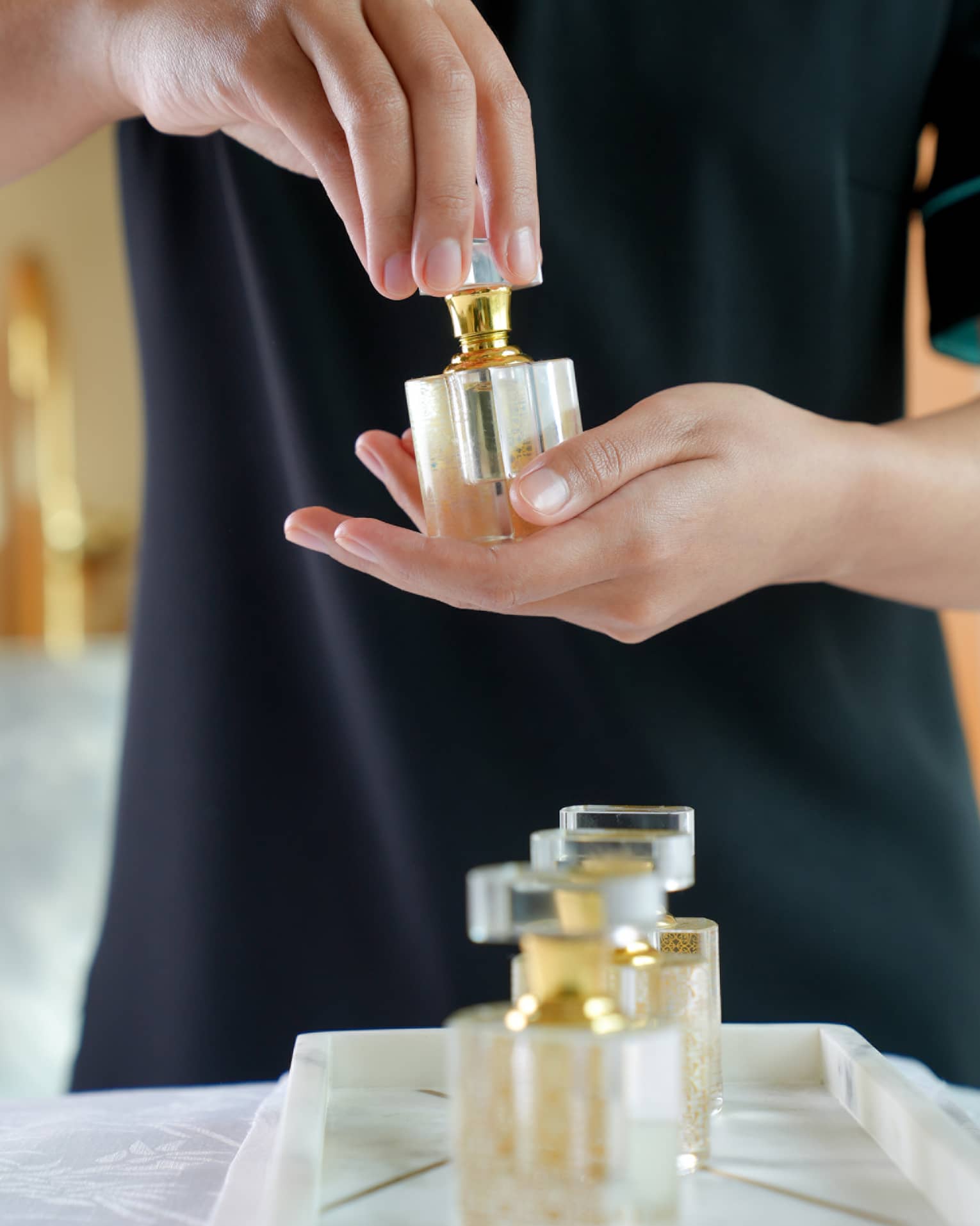 A spa attendant holding a square, glass fragrance bottle