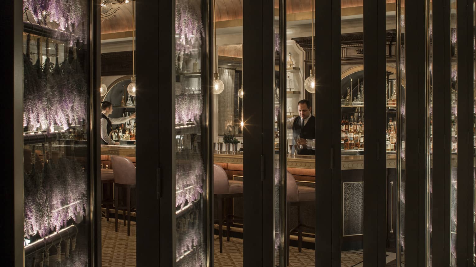 A view of a restaurant bar through several long rectangular pillars.