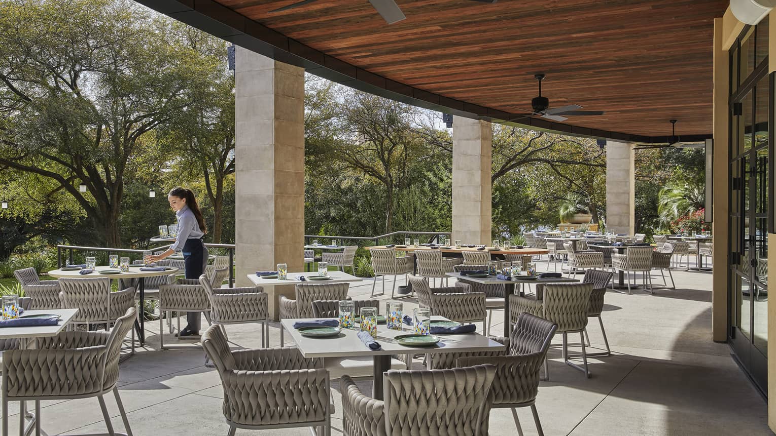 A waitress arranges place-settings on the shaded outdoor dining terrace at Ciclo.