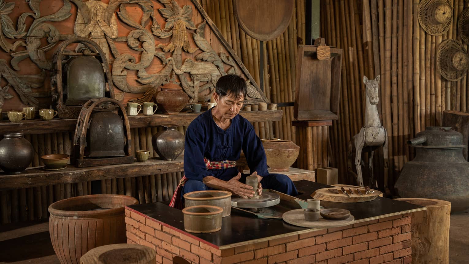 A man in a pottery studio holding a piece of grey clay.
