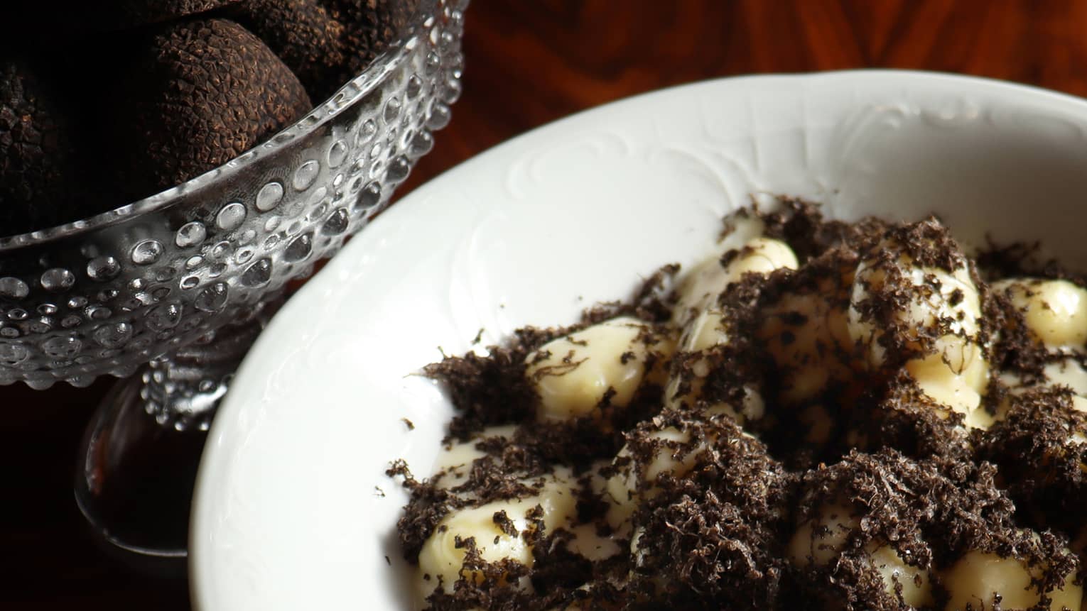 Gnocchi in a dark sauce in a white bowl.