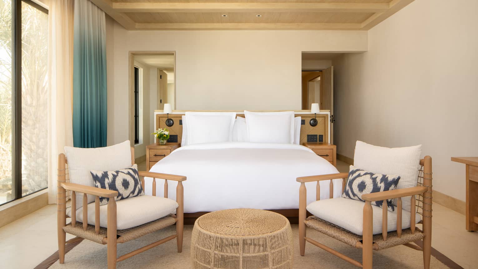 Luxury villa bedroom with king bed and two chairs, beamed ceiling, and windows, at Four Seasons Resort Cabo San Lucas at Cabo Del Sol