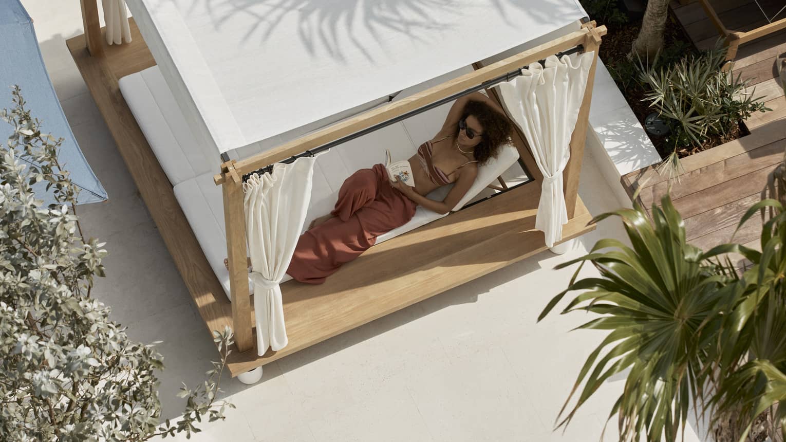 Aerial view of woman lounging in a covered poolside daybed
