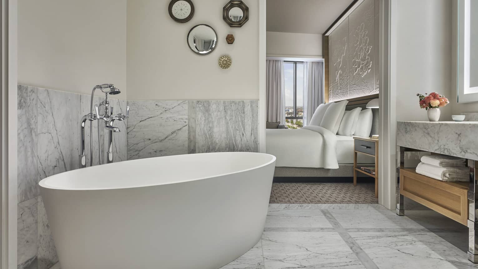 Premier King bathroom with marble counters and floors, large soaking tub, lighted mirror, wooden under-sink storage with towels
