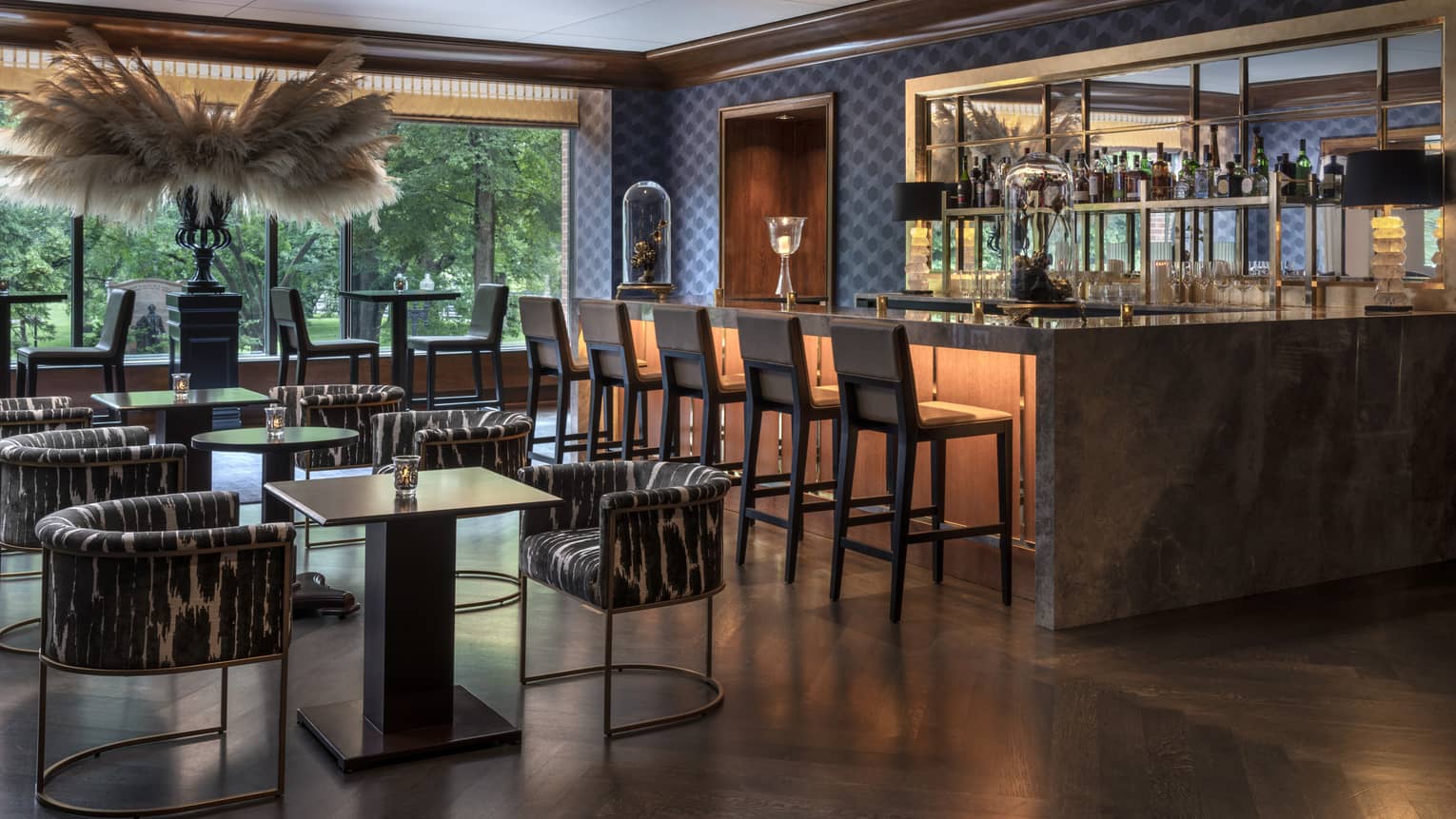 A dining area with small tables and a large bar with black stools.
