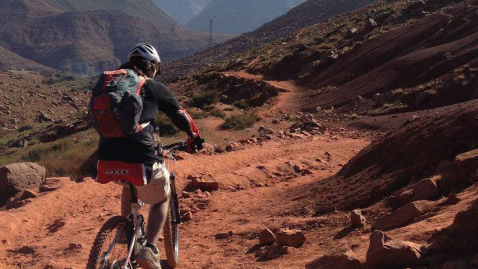 Cyclist riding along dirt trail high up in mountain range