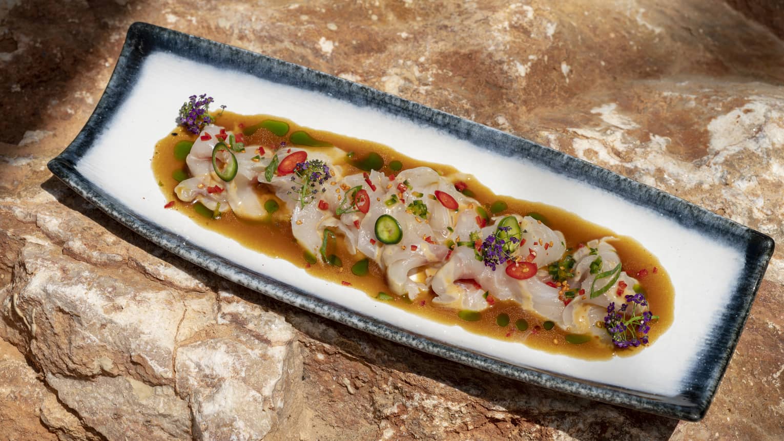 Nikkei Tiradito with Sea Bass, Black Truffle Ponzu and Aji Panca on rectangular dish