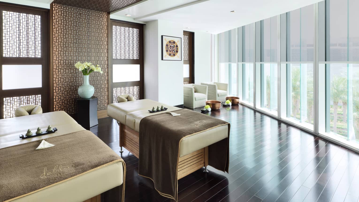 A couple's treatment room with floor-to-ceiling windows overlooking a garden. 