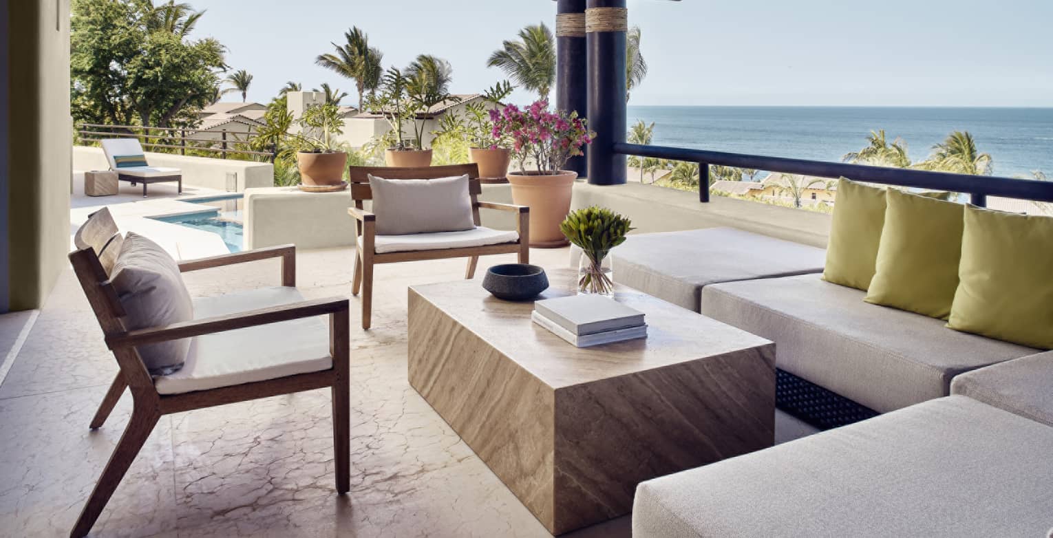 Covered, ocean-view outdoor lounge with sectional sofa and two chairs