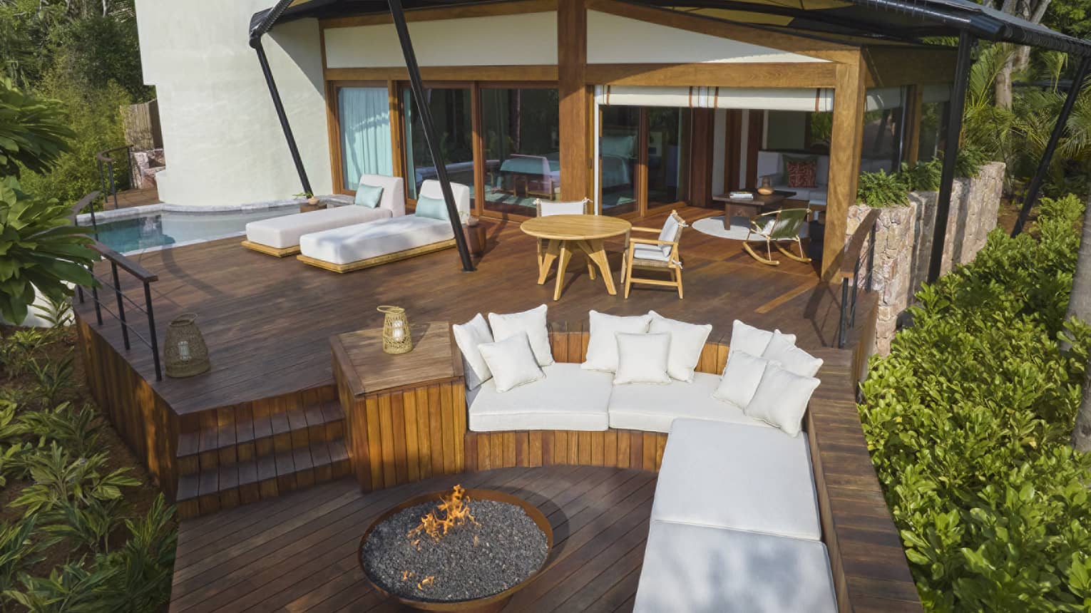 Luxury tent nestled within tropical forest, with outdoor lounge seating, fire pit and plunge pool