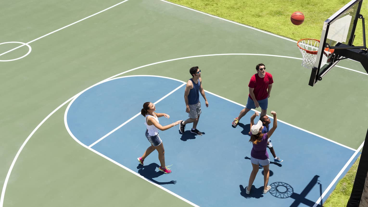 Aerial view of group of friends on basketball court, throwing ball in net