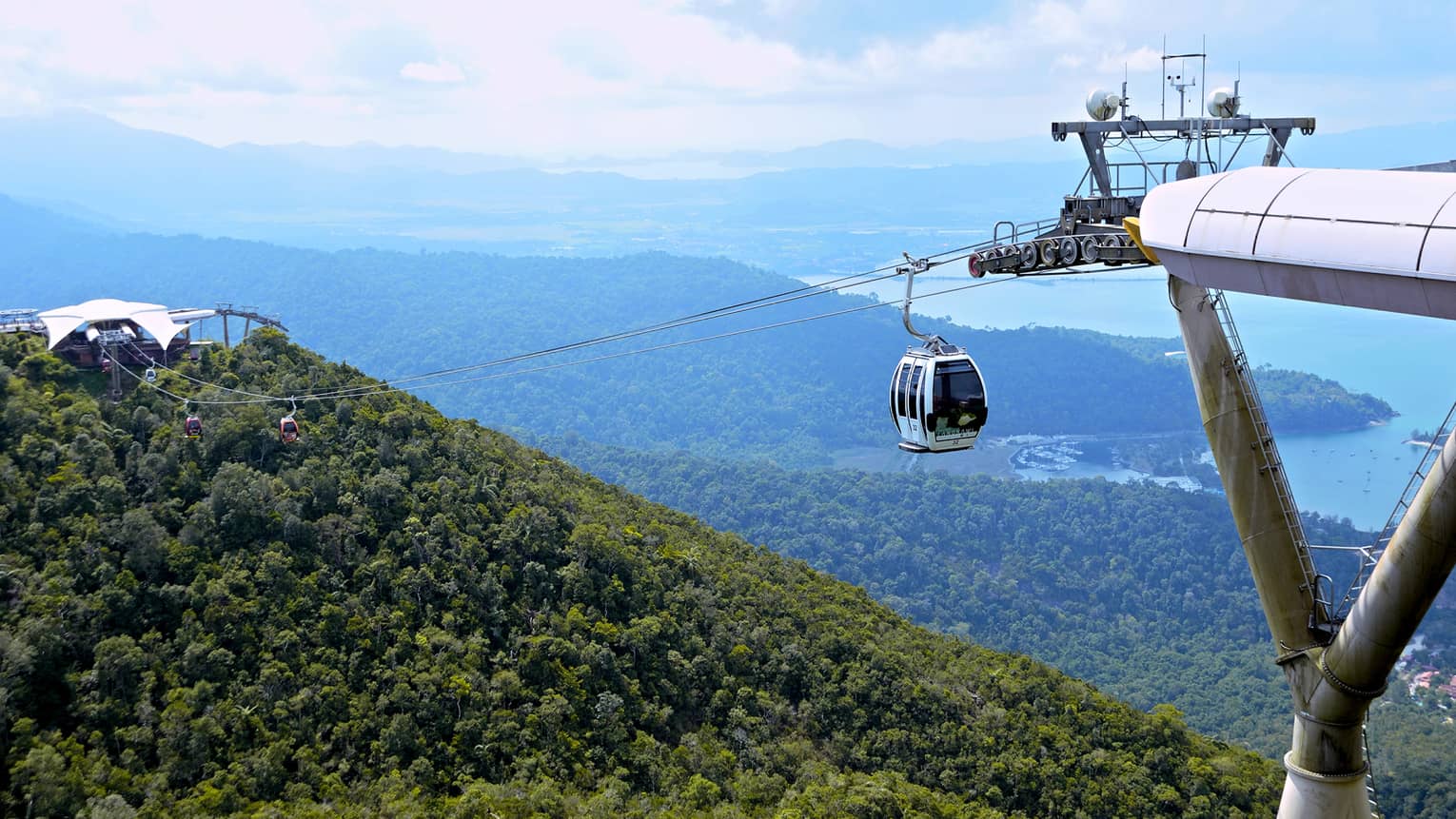 Cable car on Sky Bridge line hanging high above canopy of trees, mountains