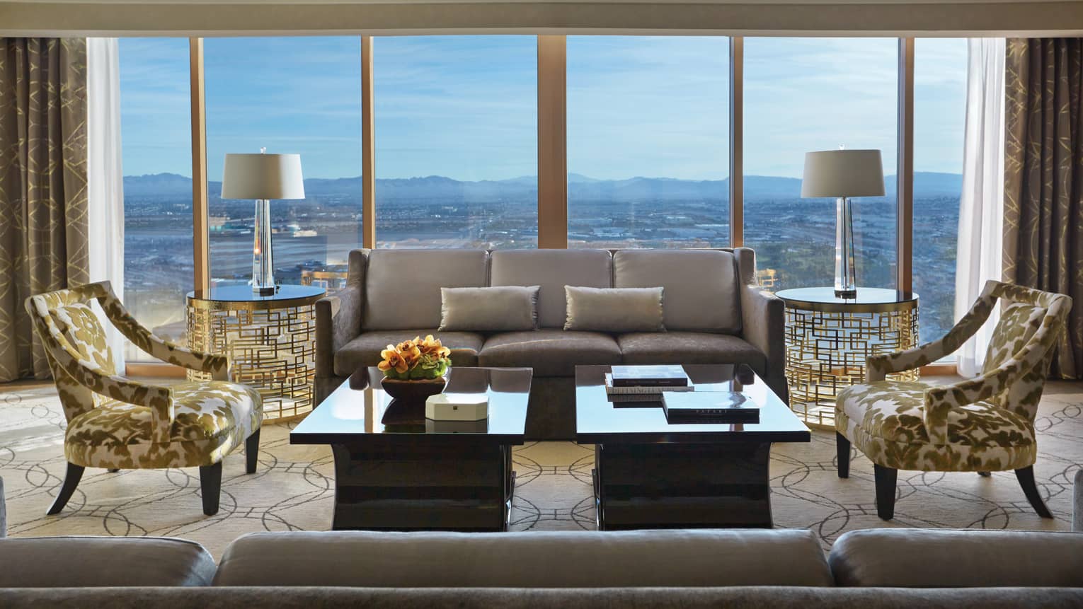 Valley-View Suite silver sofas, gold accent chairs, wall of windows with sweeping Las Vegas views