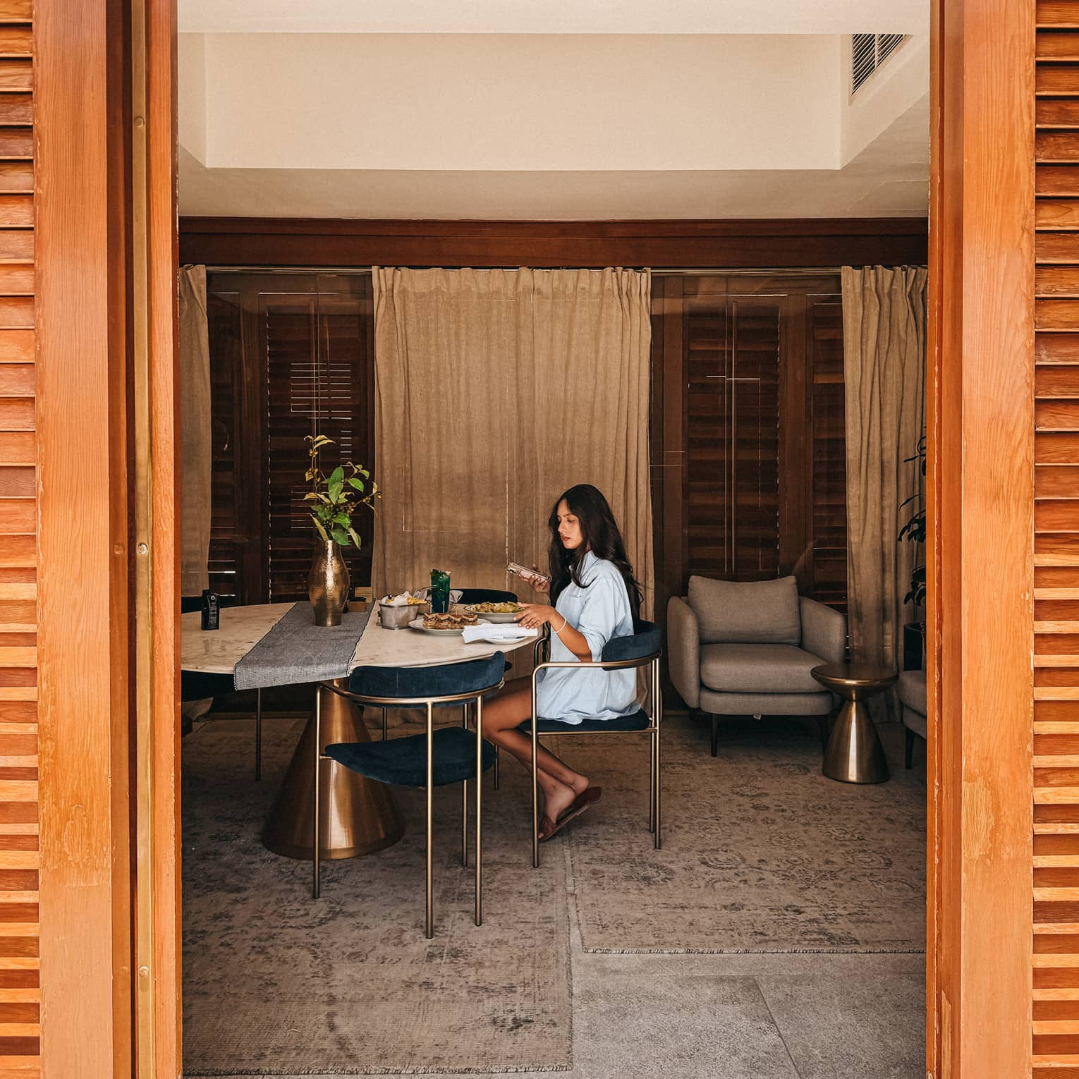 Guest sits inside a cabana at a marble dining table