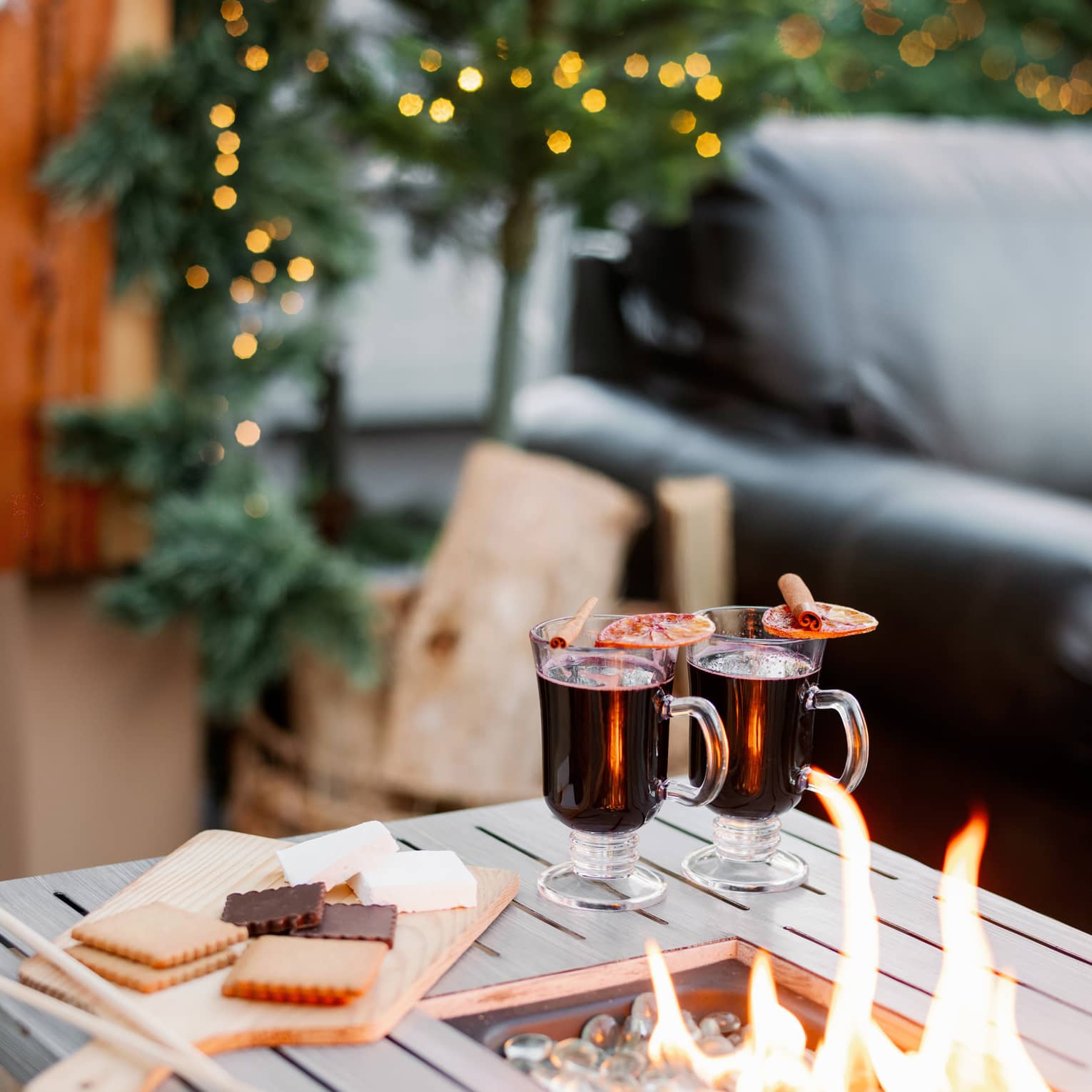 Fire pit with s?mores ingredients and two mugs placed on the side.