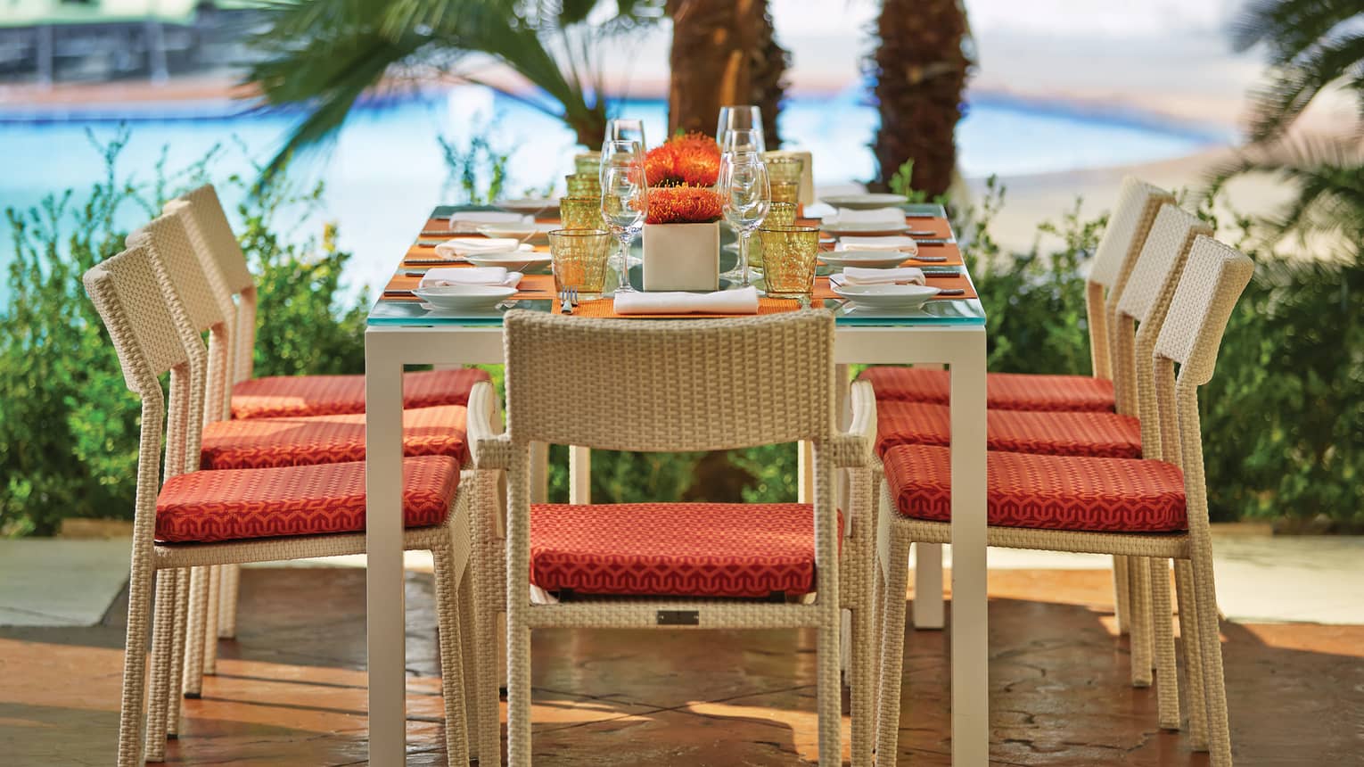 Veranda Restaurant patio dining table, chairs with red cushions, palms in background