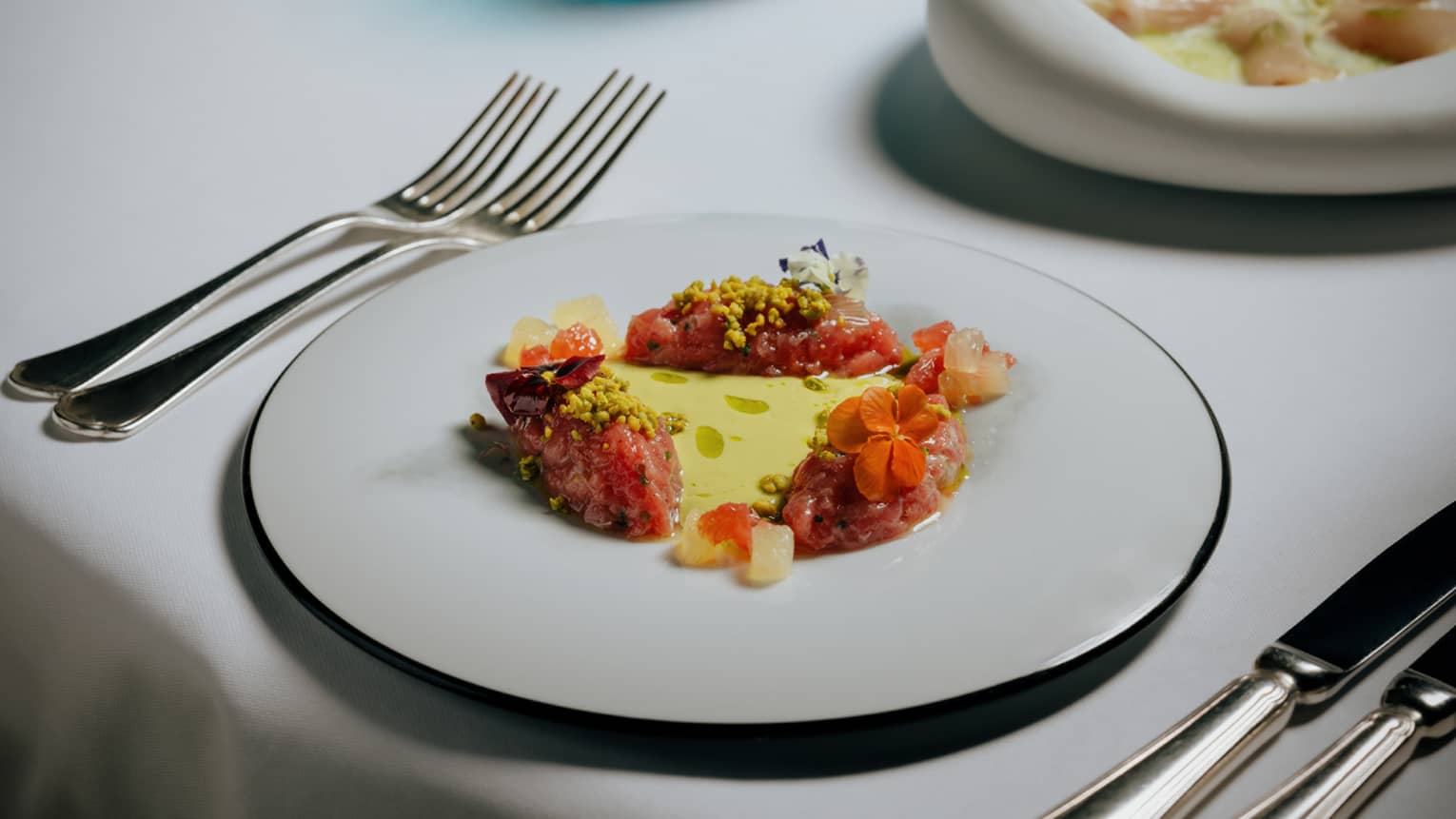 Tuna tartare plated on a white plate with a silver rim