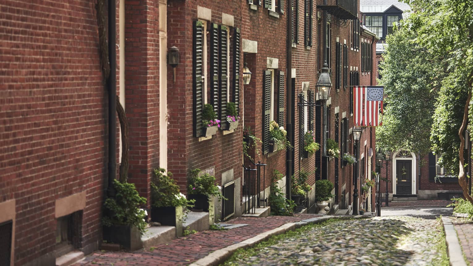 A cobblestone alley in Beacon Hill, lined with red brick residential buildings 