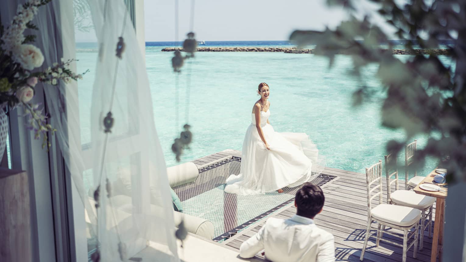 Bride and groom relax before their reception in their overwater wedding bungalow with glass-bottom floor