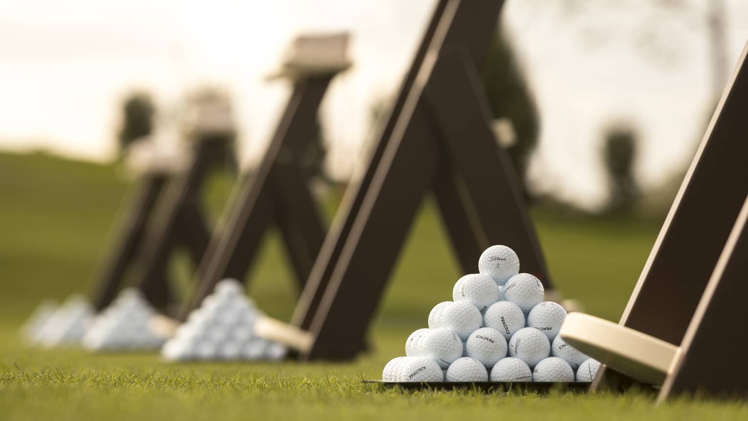 Stacks of white golf balls on lawn in front of wood panels