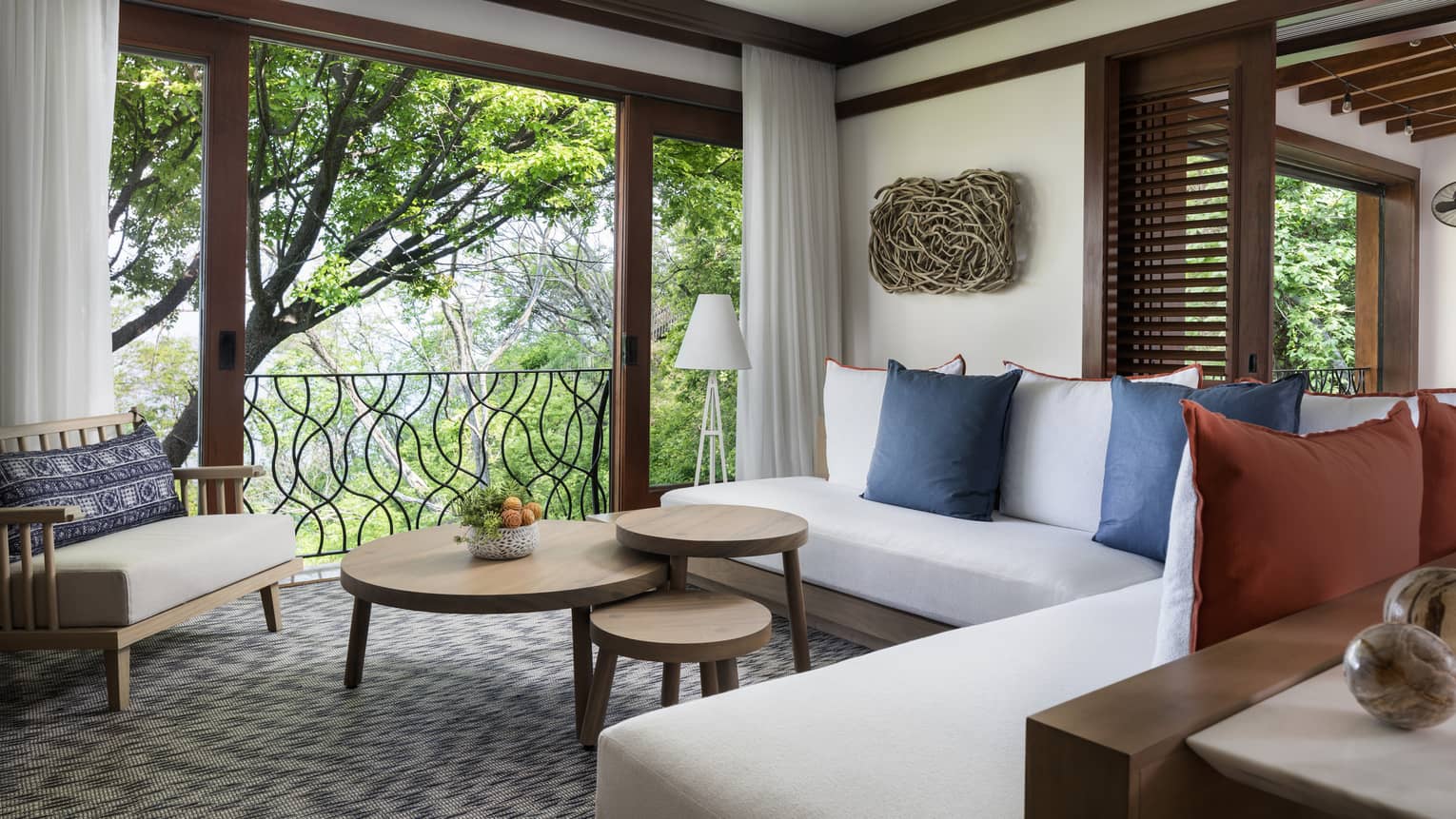 Pacifico Two-Bedroom Resort Residence living room with white L-shaped sofa, three-tiered table by large open wall