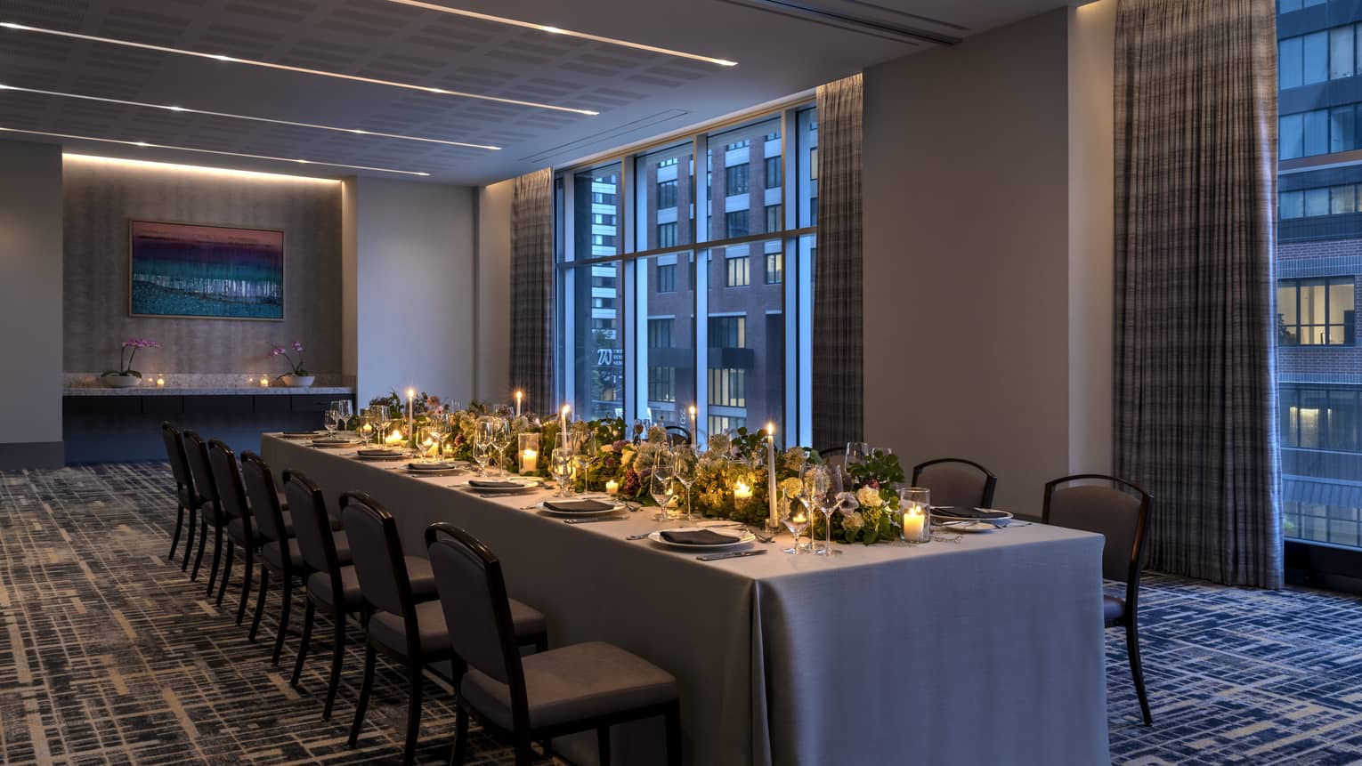 A long table with candles and flowers in a dimly lit room.