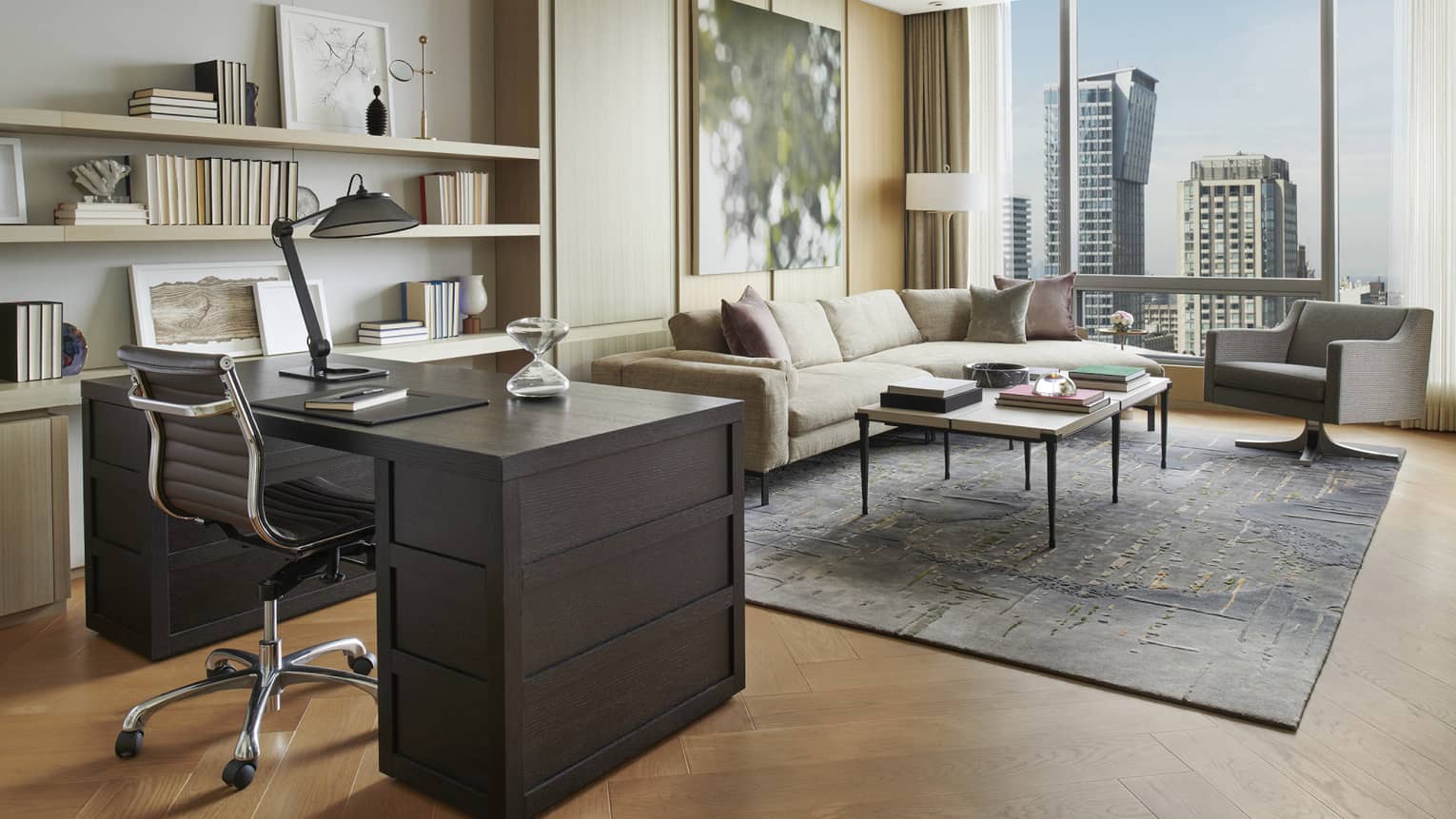 A brown mahogany desk overlooks a seating area with floor-to-ceiling windows.