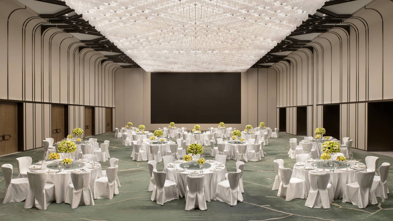 Grand ballroom with a ceiling-sized lighting display, white tables and chairs set up for a banquet event