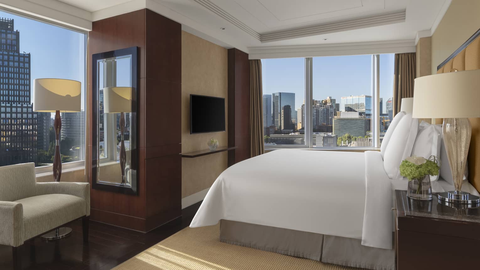 Hotel room with king bed, arm chair and two walls of windows