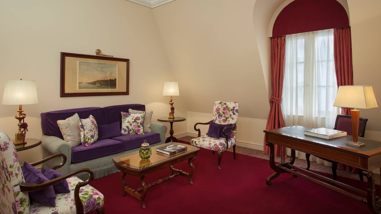 La Mansión Diplomatic Executive Suite deep red carpet, blue-and-purple sofa, floral armchairs