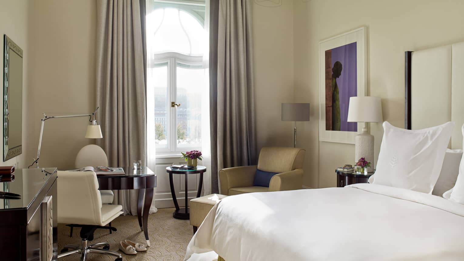 Danube River-View Room bed with white linens, cream-coloured desk chair and armchair, tall picture window, curtains