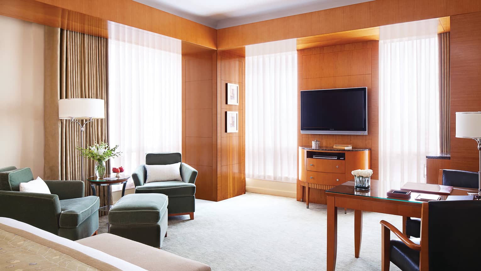 Executive Premier Room wood panel walls, sunny windows with sheer curtains, bed, TV, chairs