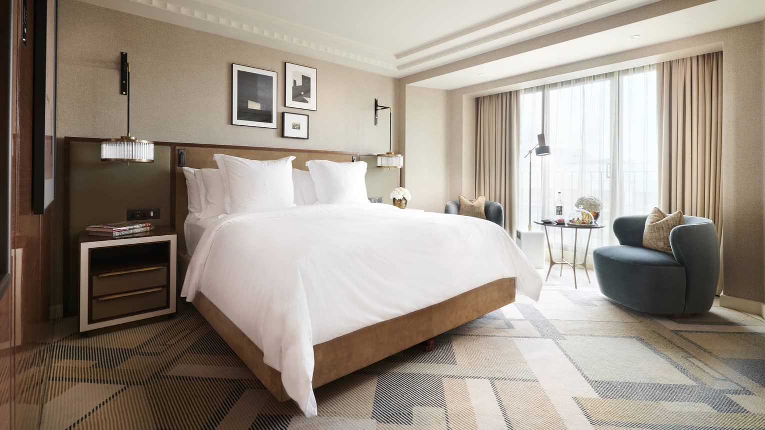 Floor to ceiling windows let natural light into the Deluxe King Room, furnished with a modern king bed, a modern egg-shaped blue chair and side table