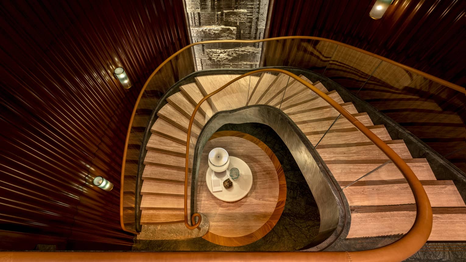Aerial view of wooden staircase with gold bannisters curving to lower floor