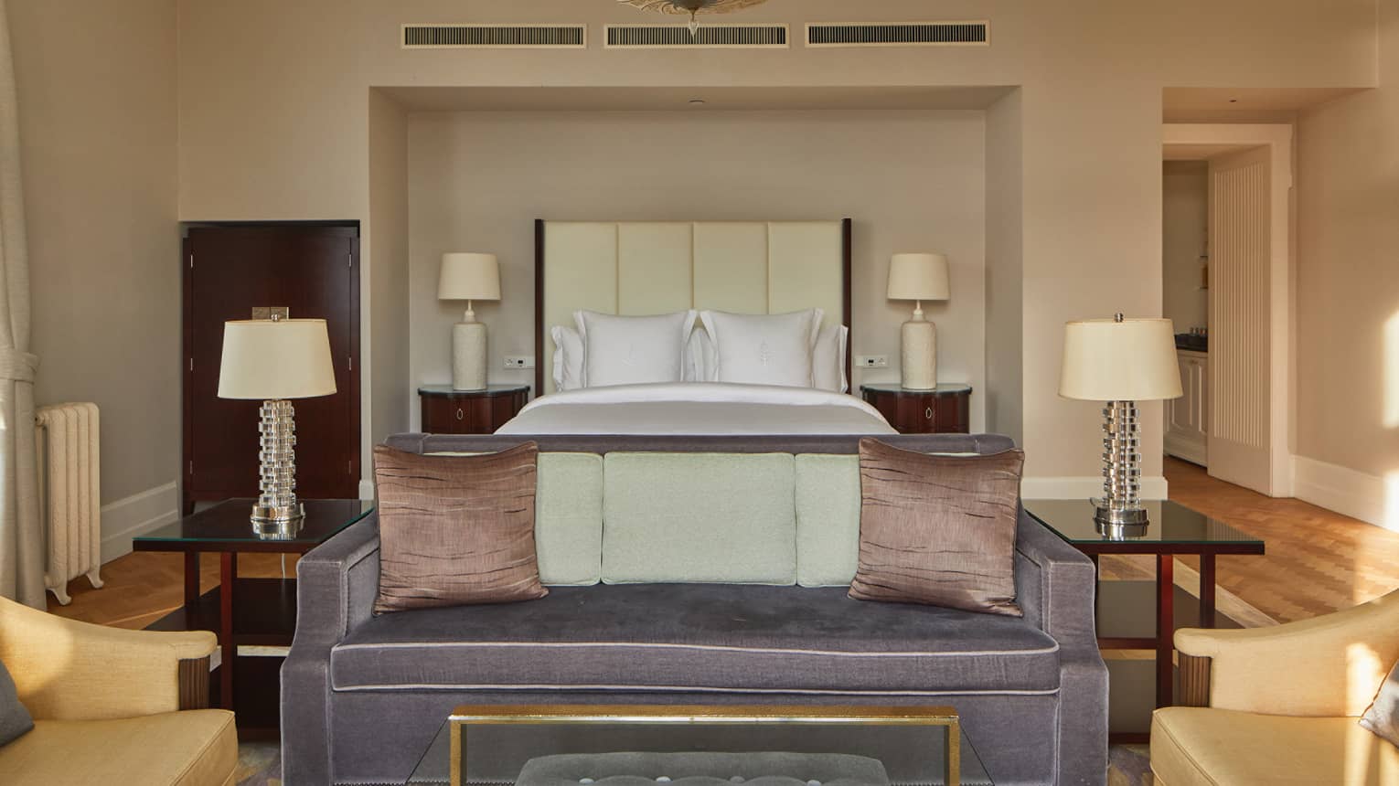 A room with a bed, a sofa, chairs and four lamps.