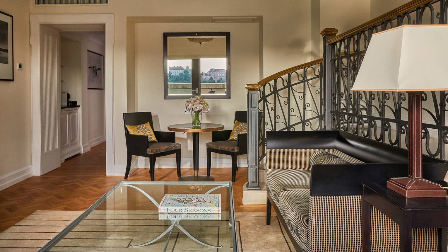 A sitting area near stairs, with a sofa, coffee table, and a small table with two chairs.