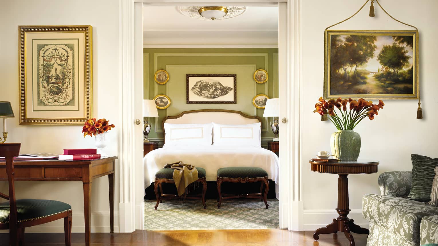 Four Seasons Executive Suite desk, chair by bedroom doorway, bed and scarf across green footstools