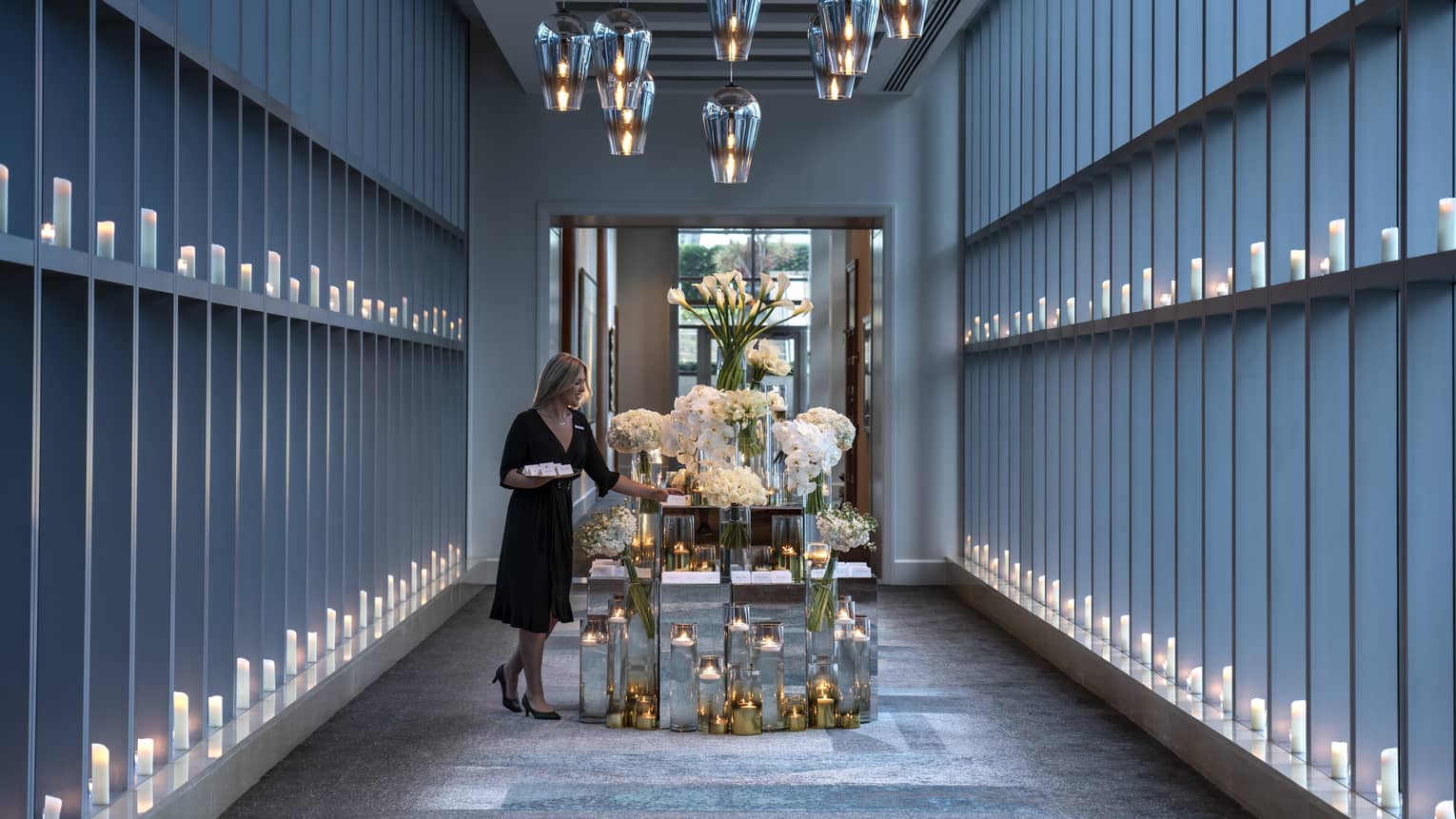 Hotel staff sets table with large flower arrangements in modern Sky Bridge