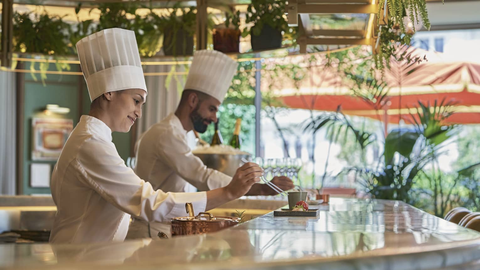 Male and female chef in action at bar counter of restaruant