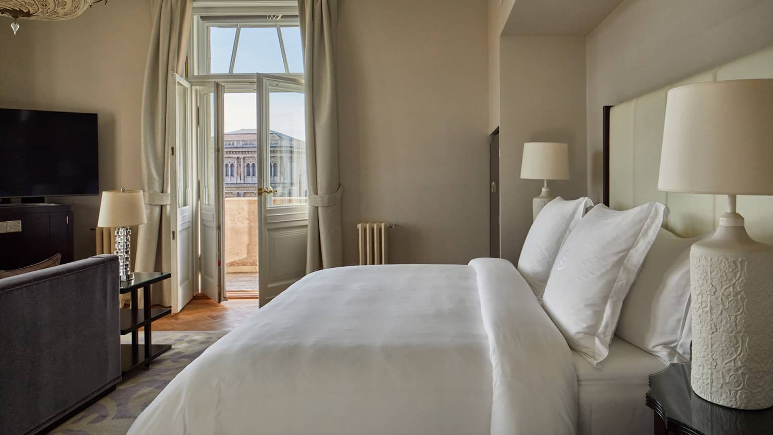 A room with a bed, open door to outside, lamps, and television.