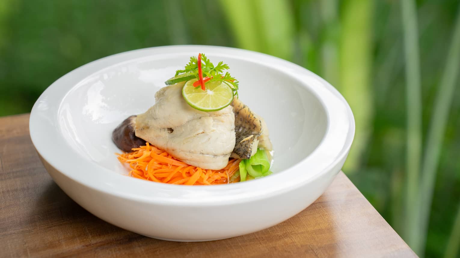 Steamed Gulf of Thailand Sea Bass with Lime and Garlic in white bowl
