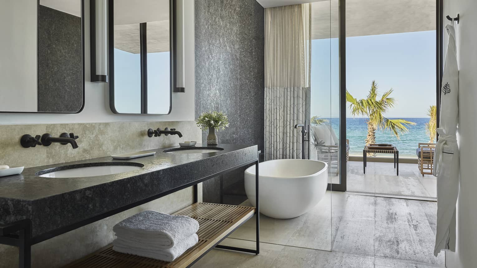 A bathroom with large sliding glass door, a sink with shelf, mirrors and bathtub.