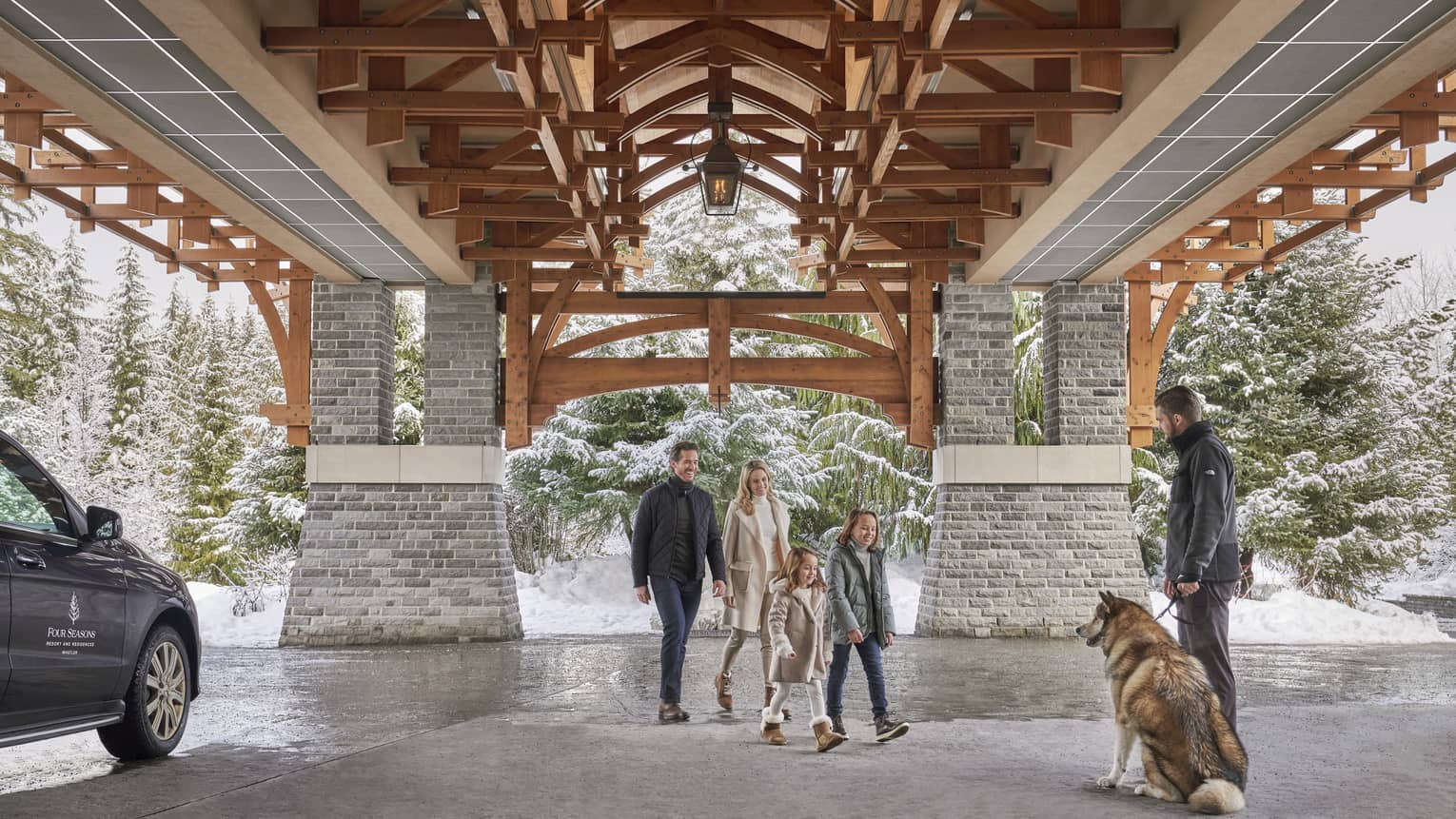 A family arrives at Four Season Whistler with a backdrop of snowy trees.