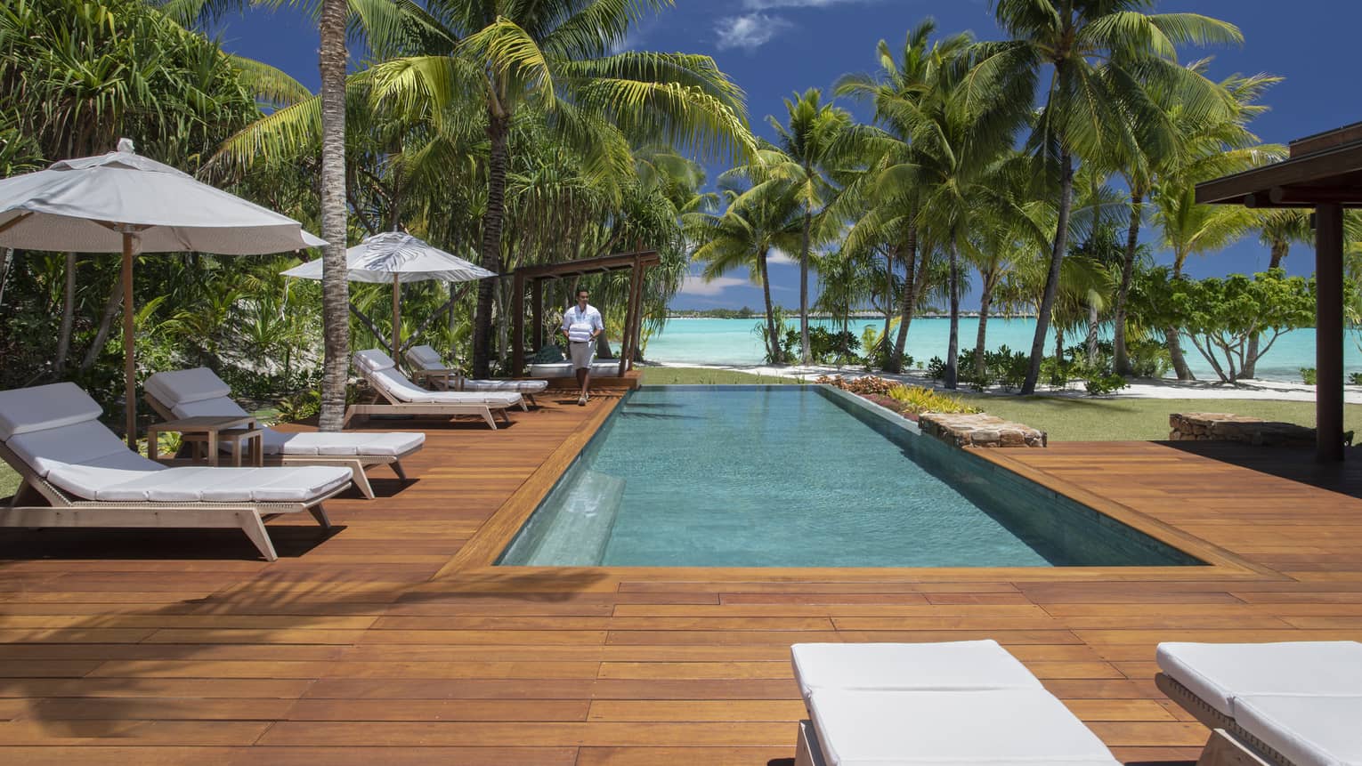 Villa's private pool with a lagoon view, surrounded by a wooden deck with sun chairs