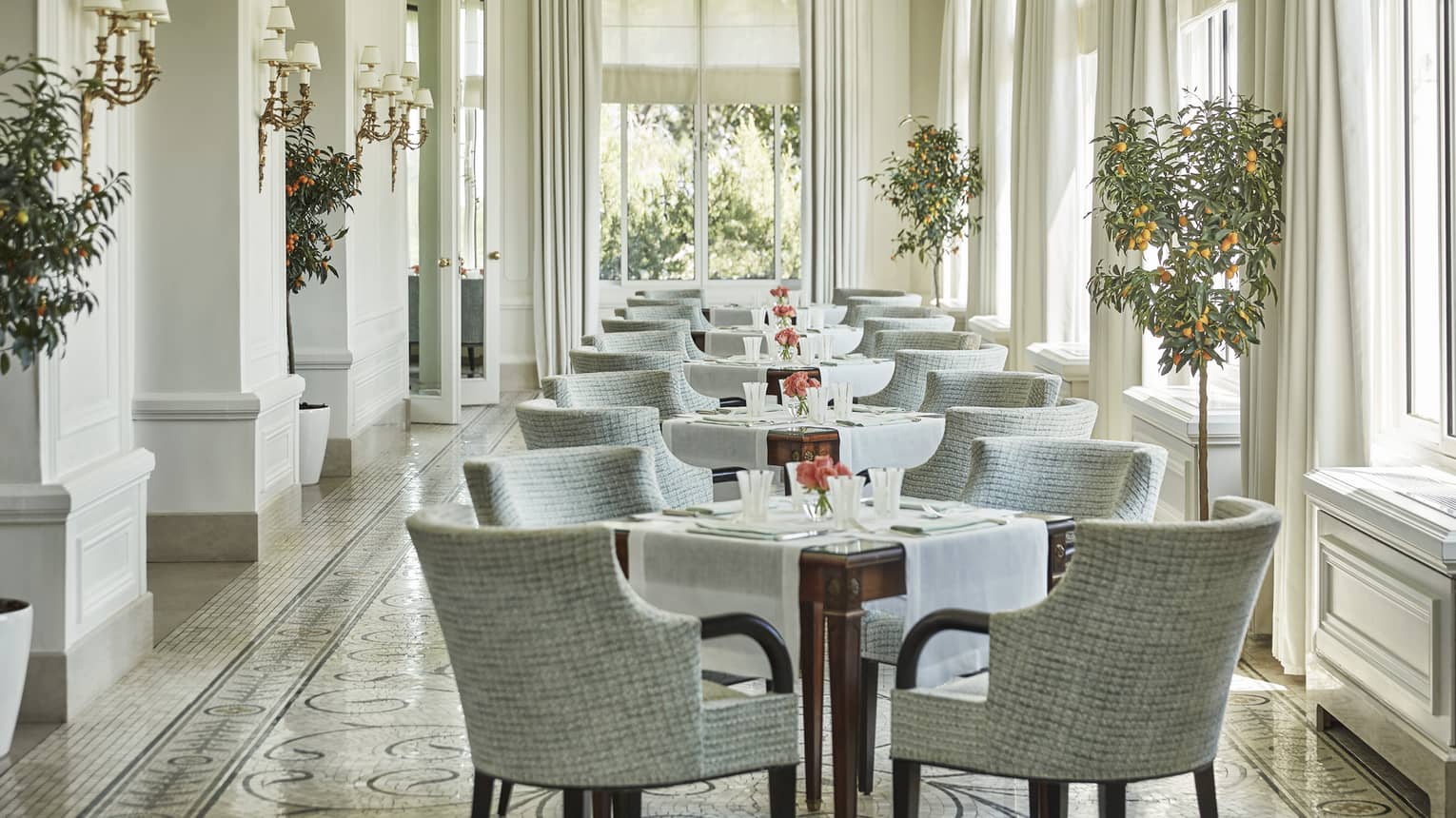 Grey chairs around tables in sunny Le Veranda dining room