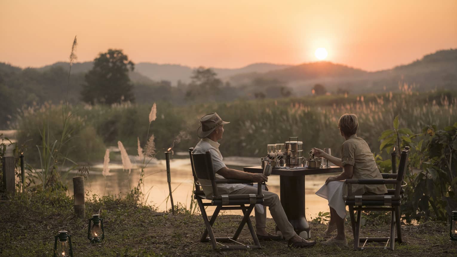 Couple enjoys Camp Bush Dinner along river at sunset