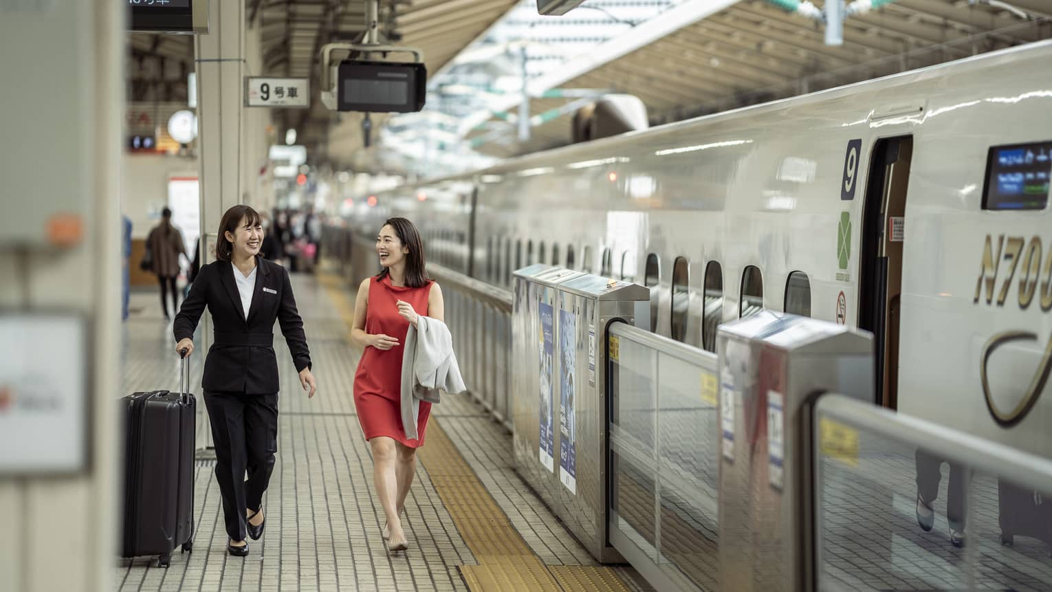 Train station greeter walks with female guest along the train platform